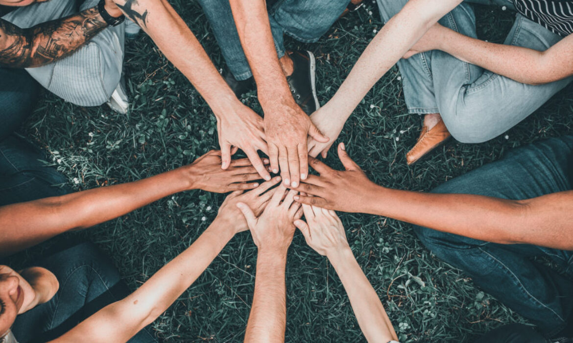 People stacking hands together in the park