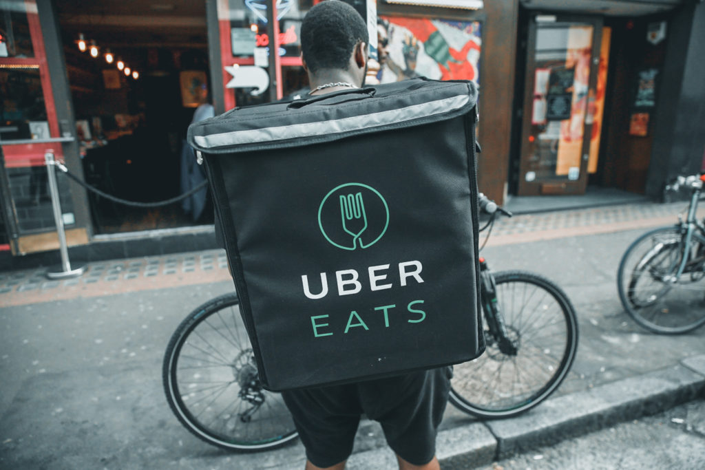 An UberEATS food delivery courier stands in front of his bike in London