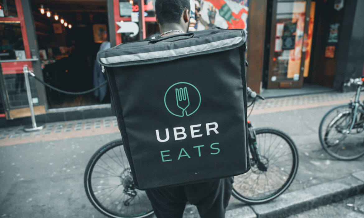 An UberEATS food delivery courier stands in front of his bike in London