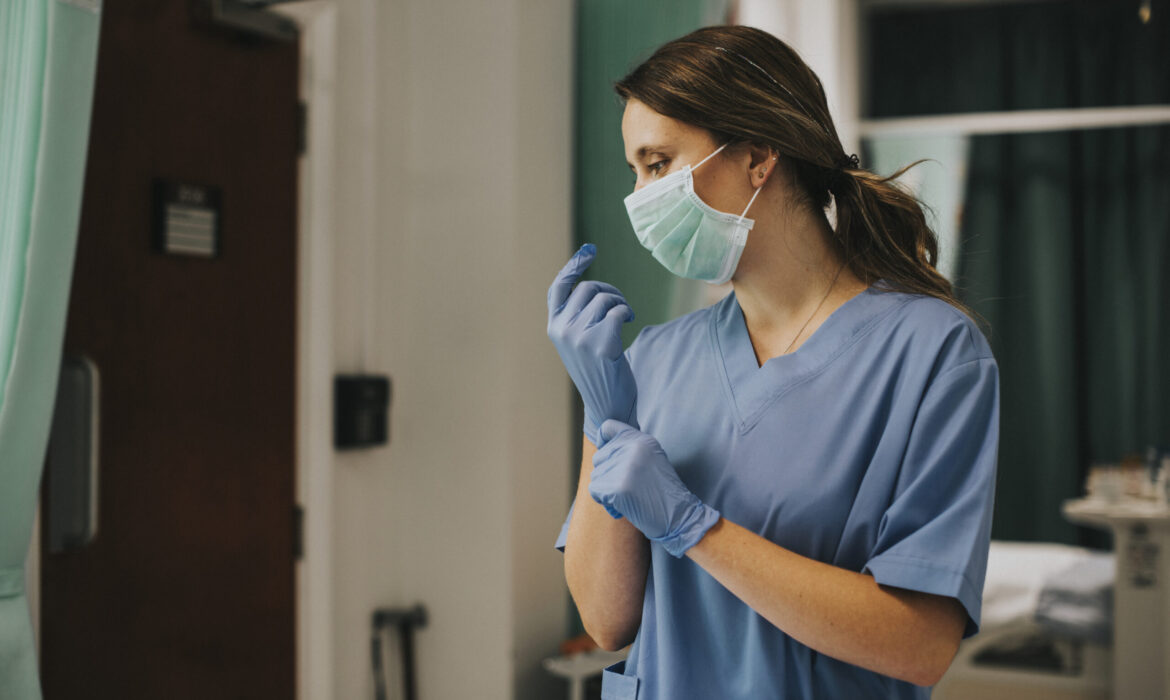 Female nurse with a mask putting on gloves