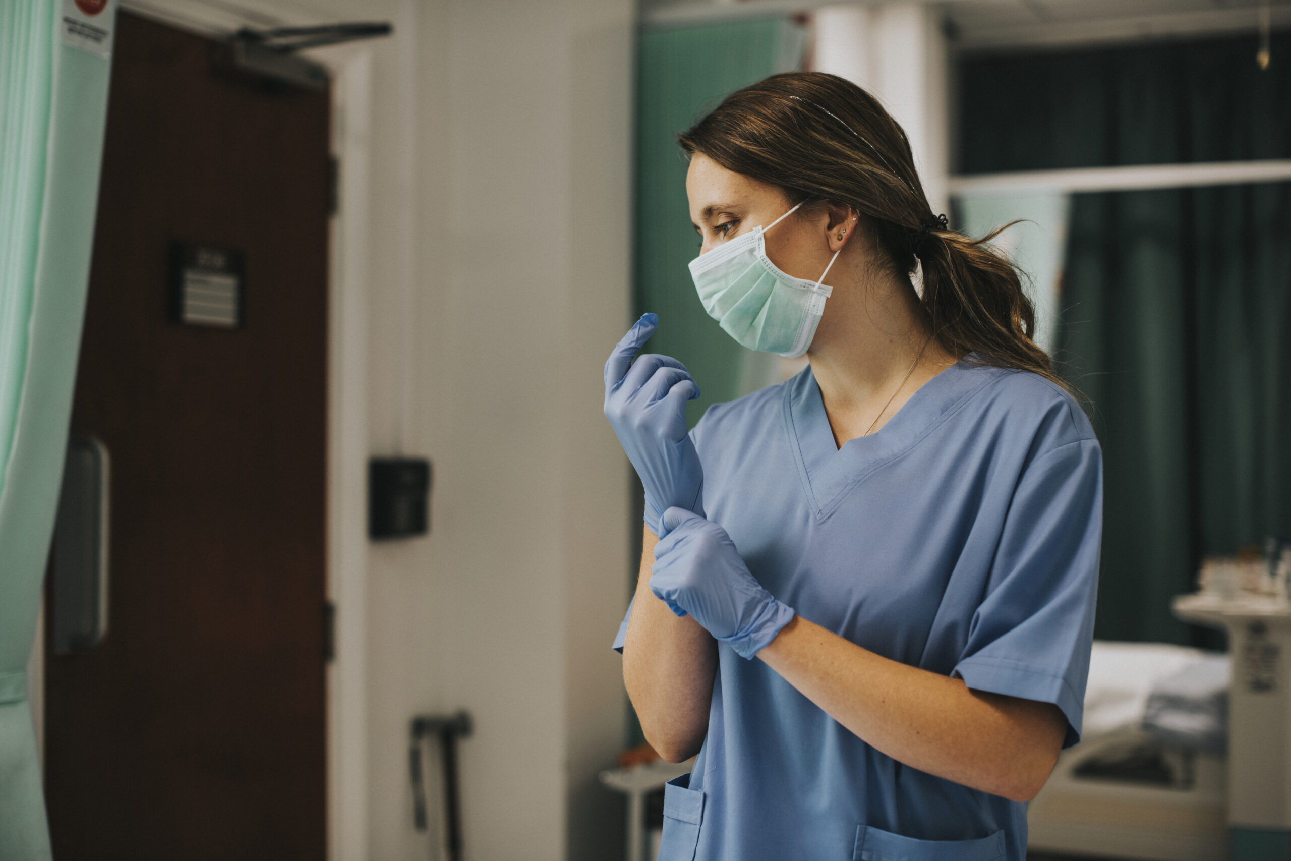 Female nurse with a mask putting on gloves